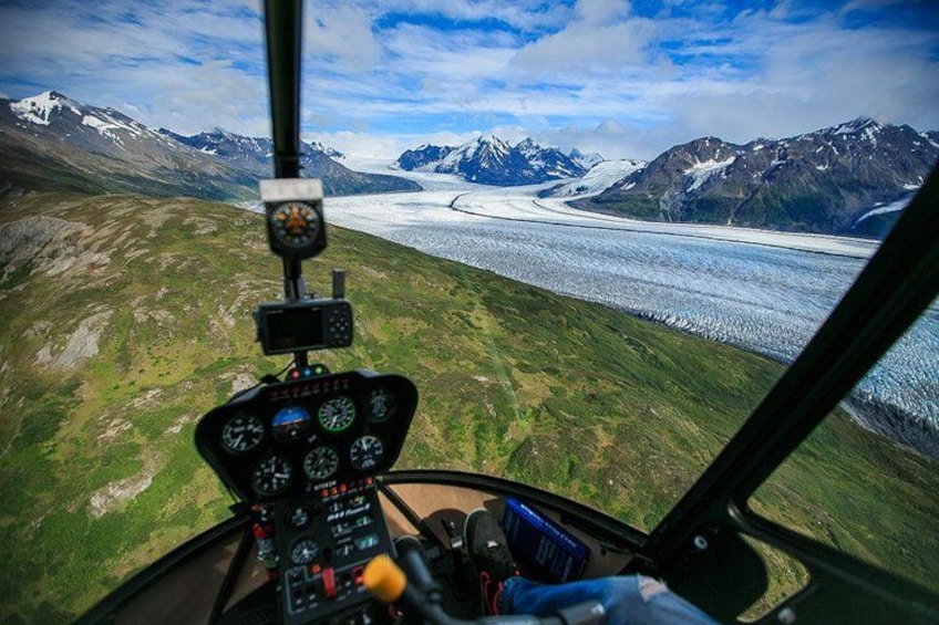 En helikoptercockpit med utsikt över en glaciär och berg. 3