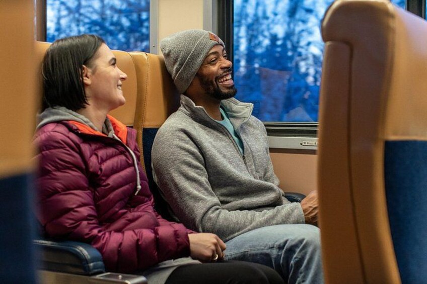 Two people sitting on a train seat, facing each other. 5