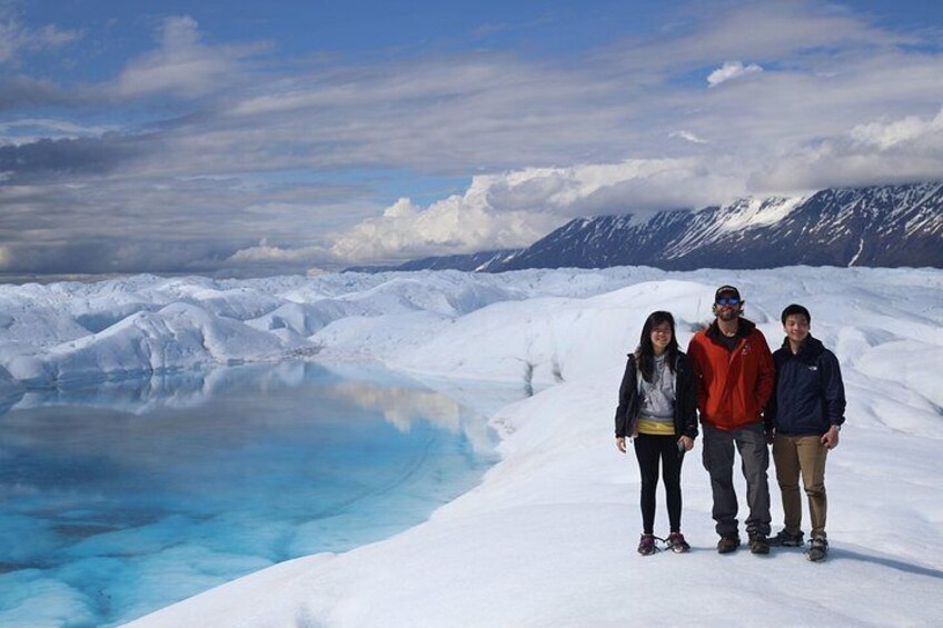 A group of people standing on a snow-covered landscape with a frozen lake and mountains in the background. 2