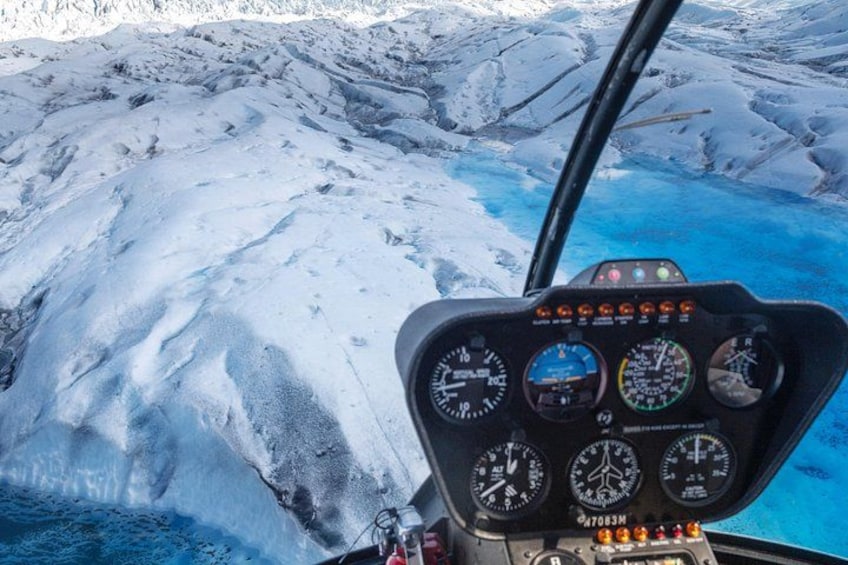 A helicopter cockpit with a snowy landscape and a glacier in the background. 2