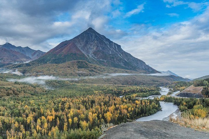A mountain landscape with a river, autumn foliage, and a cloudy sky. 3