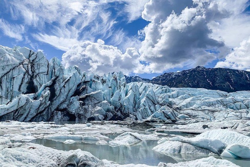 A glacier with ice formations and a mountainous background. 1