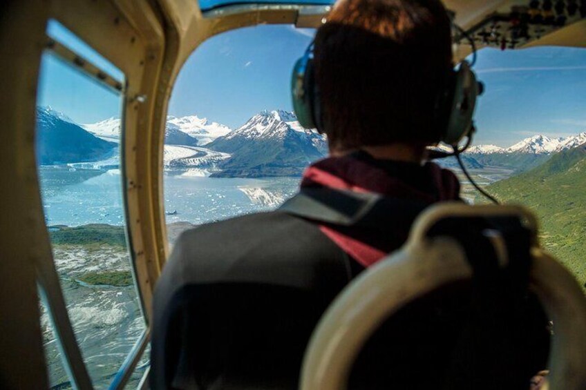 Una persona en la cabina de un helicóptero, con vistas a montañas nevadas y un glaciar. 5