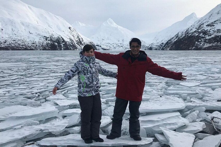 Twee mensen staan op een bevroren meer, met besneeuwde bergen op de achtergrond. 4