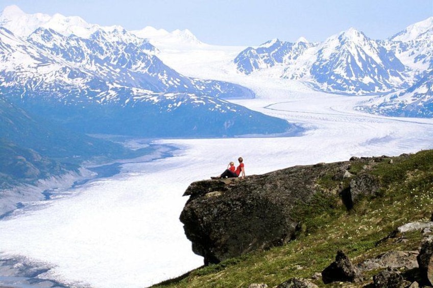 En glaciär med en person som sitter på en sten. 2