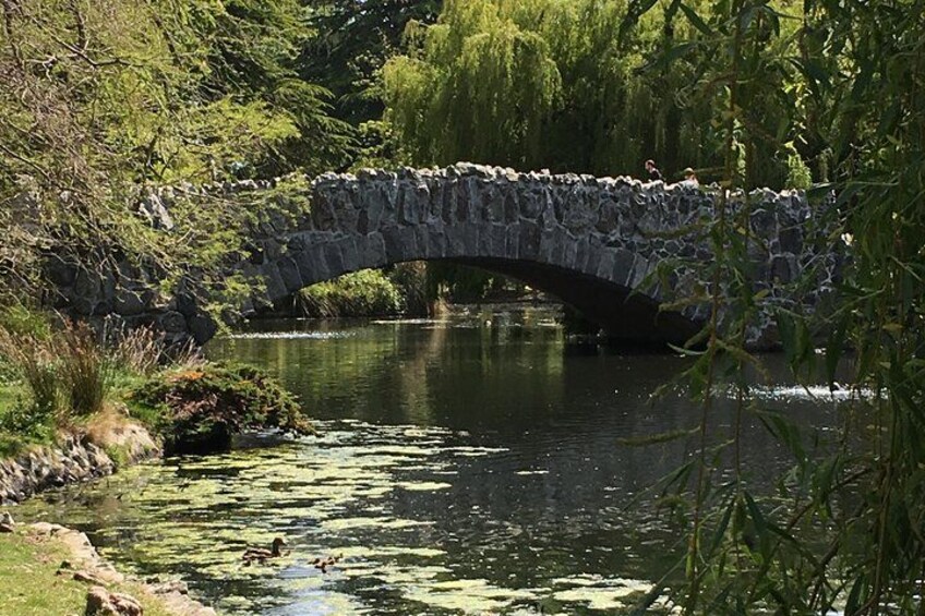 A stone bridge over a river with greenery and trees around. 5