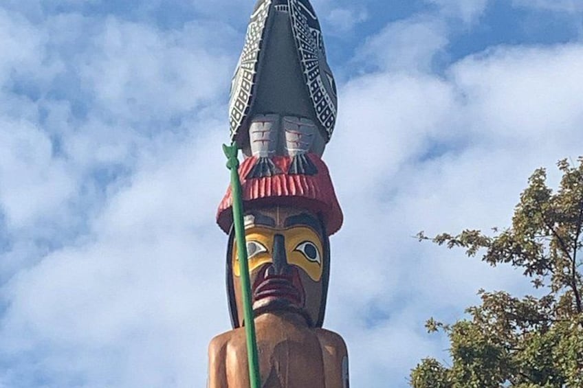 A large totem pole with a carved face and a headdress. 4