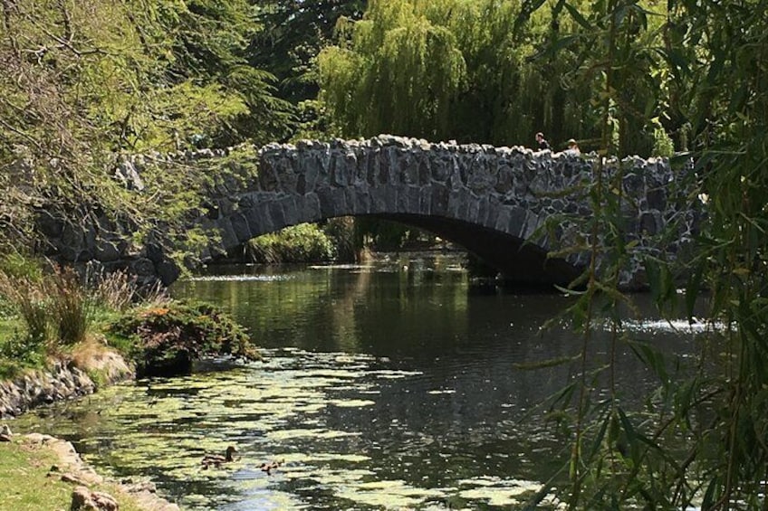 Eine Steinbrücke über einem Fluss, umgeben von Grün und Bäumen. 2