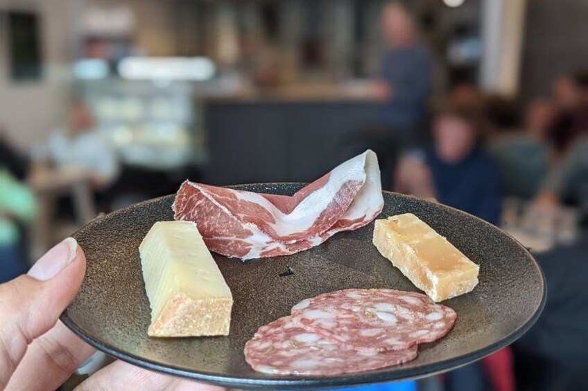 A person holding a plate with various meats and cheeses. 5