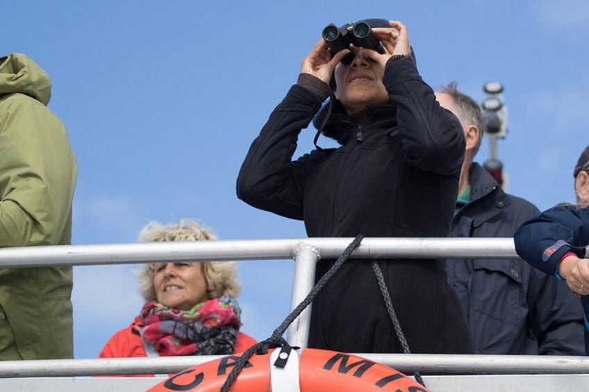 A person using binoculars, a railing, and a lifebuoy. 2