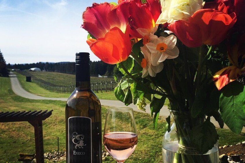 Una bottiglia di vino Enrico, un bicchiere di vino e un bouquet di fiori su un tavolo. 5