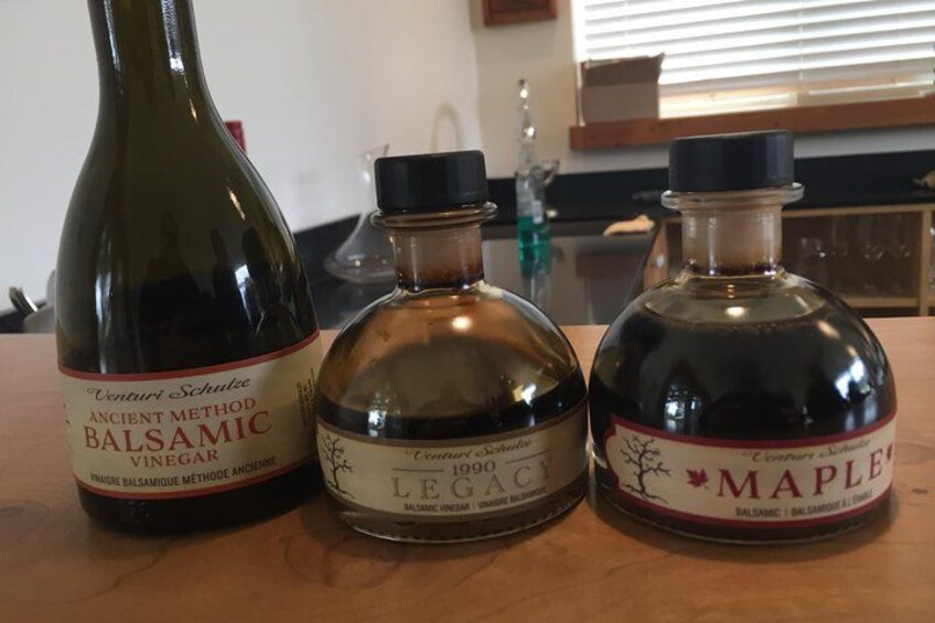 Tre bottiglie di aceto balsamico su un tavolo di legno. 4