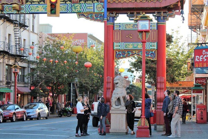 Vista de una calle con un arco rojo, una estatua y gente reunida. 4