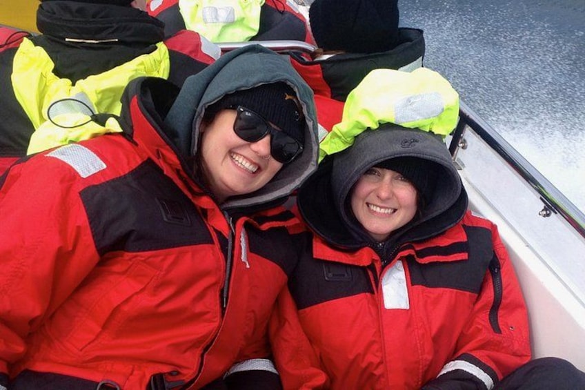 Two people in red jackets with hoods, sitting on a boat. 4
