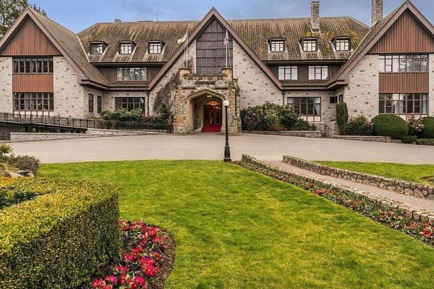 A large stone building with a red door, surrounded by well-maintained lawns and flower beds. 5