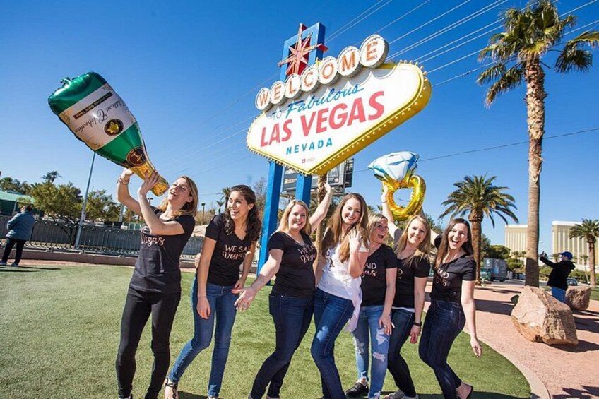 En gruppe mennesker foran Velkommenskilten i Las Vegas, med en champagneflaske. 1