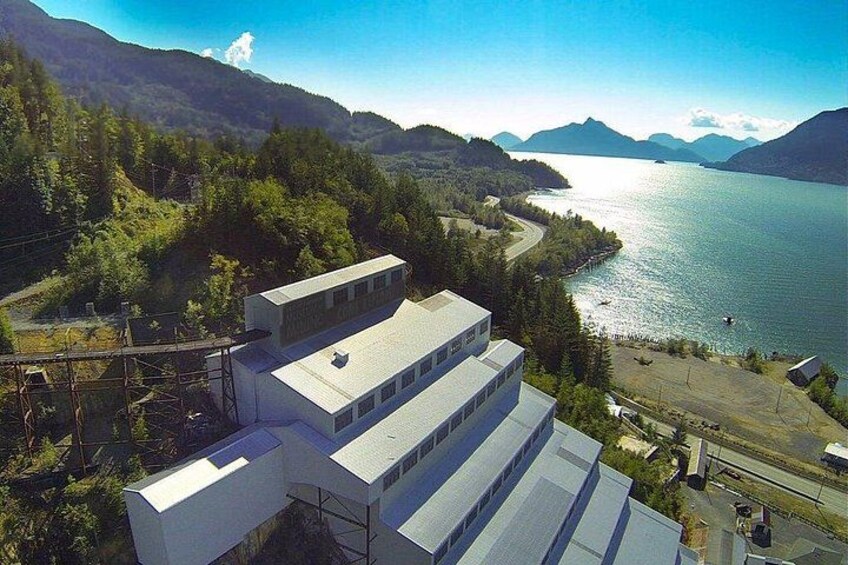 Un paisaje montañoso con un lago, un edificio blanco de techo plano y un cielo despejado. 4