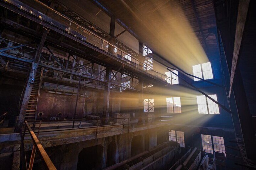 Un interior industrial con estructuras metálicas, escaleras y grandes ventanales que dejan entrar la luz natural. 2