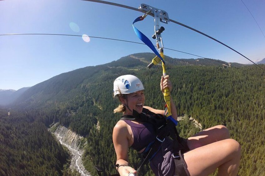 A person ziplining over a forested valley with mountains in the background. 2