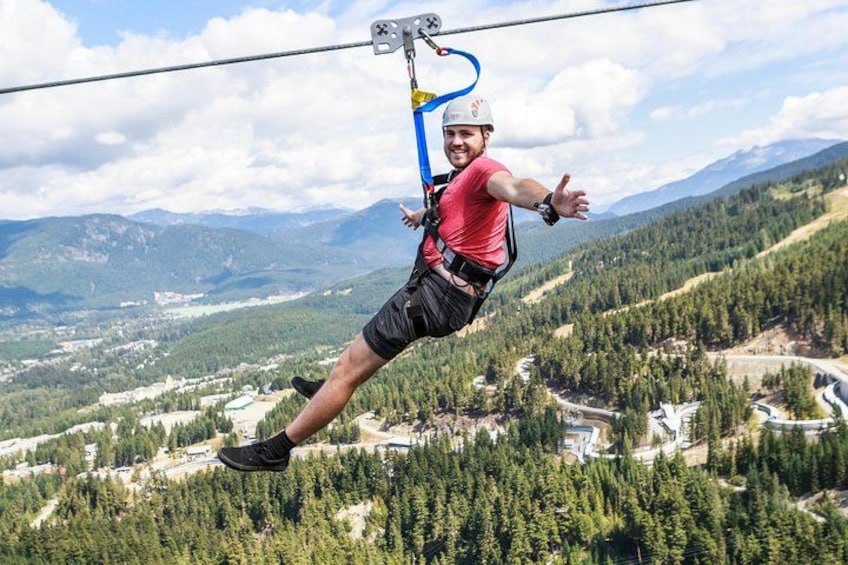 Une personne pratiquant le saut à l’élastique avec un harnais et un casque, surplombant un paysage montagneux avec de denses forêts et une route sinueuse en contrebas. 3
