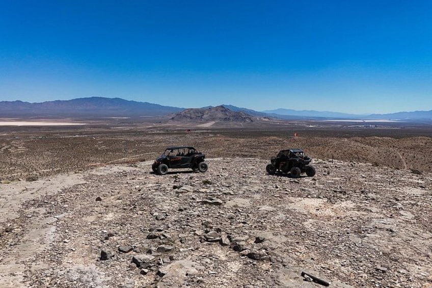 A desert landscape with two off-road vehicles and distant mountains. 4