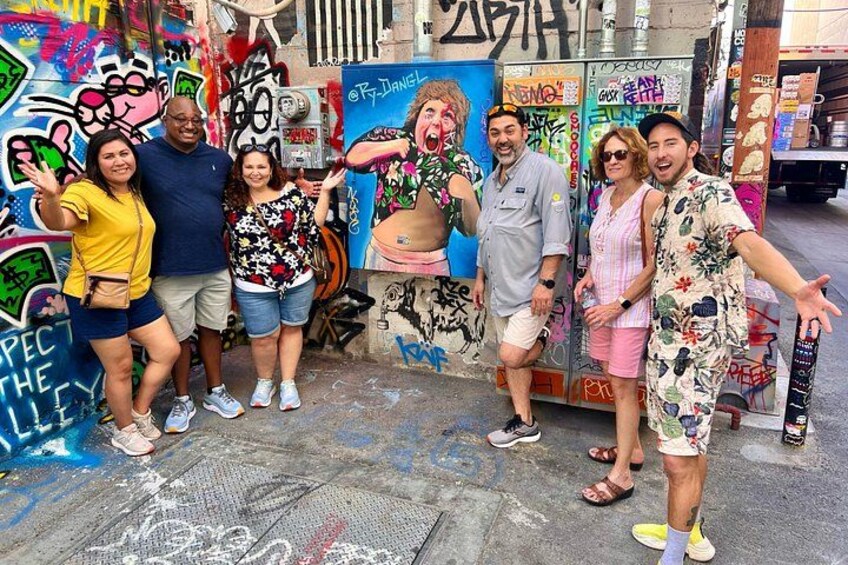 A group of people posing in front of a graffiti-covered wall. 4