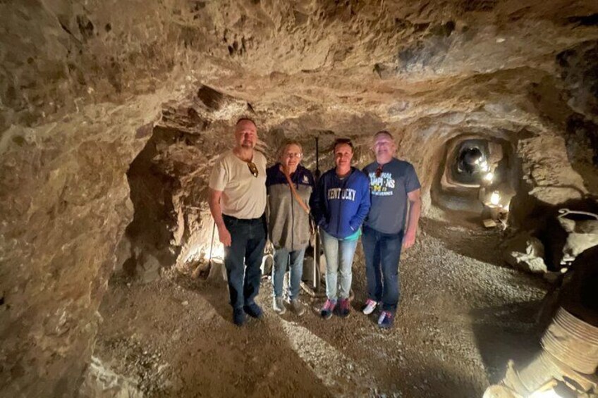 Un grupo de personas de pie en una cueva con paredes rocosas y una pequeña abertura. 2