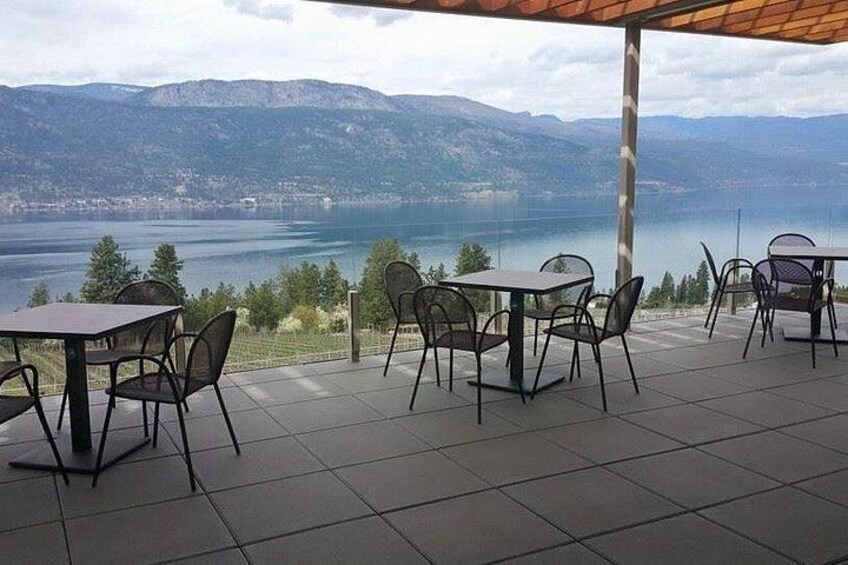 Terraza exterior con mesas y sillas con vista a un lago y montañas. 2