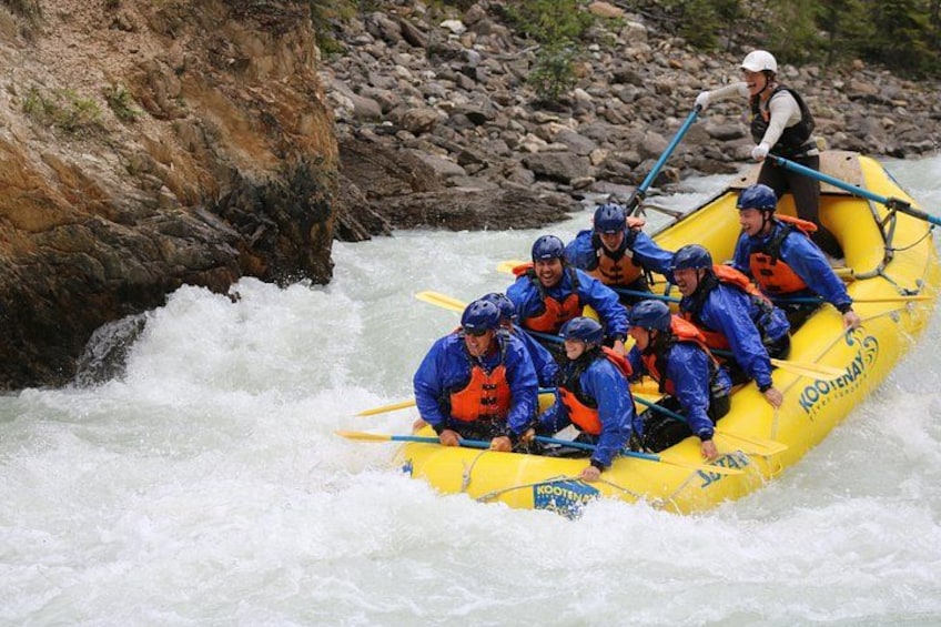 A group of people in a yellow raft navigating a white water river. 5