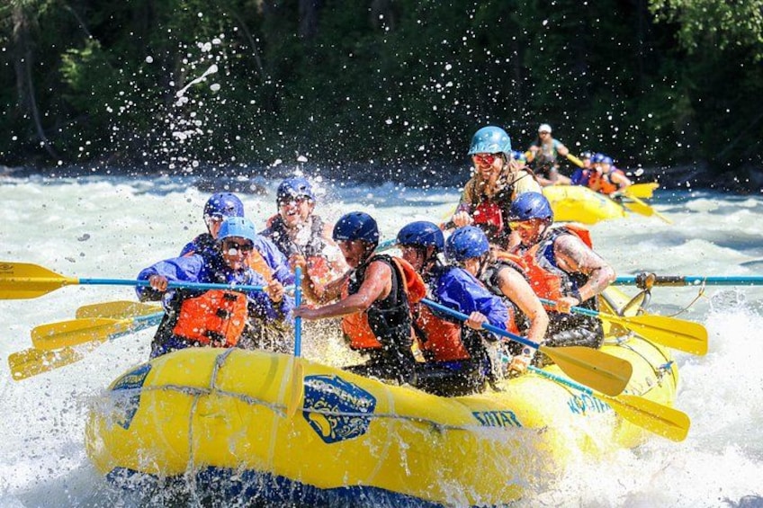 A group of people in a yellow raft navigating through whitewater rapids. 3
