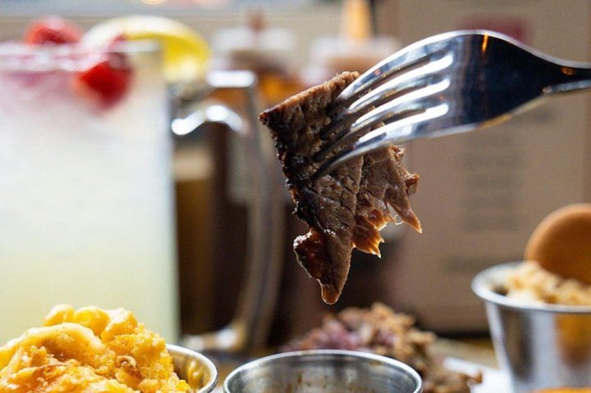 A fork lifting a piece of meat, likely beef, with a blurred background suggesting a dining setting. 5