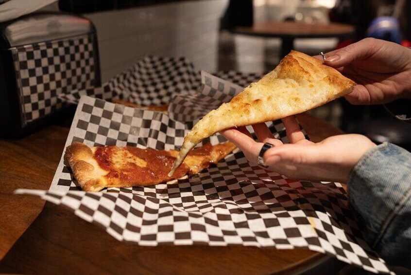 A person holding a slice of pizza on a checkered paper. 3