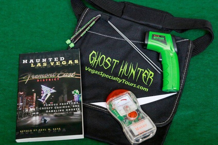 Un libro titulado 'Haunted Las Vegas', una linterna verde, un frasco de gel antibacterial y una bolsa negra con el texto 'Ghost Hunter'. 3