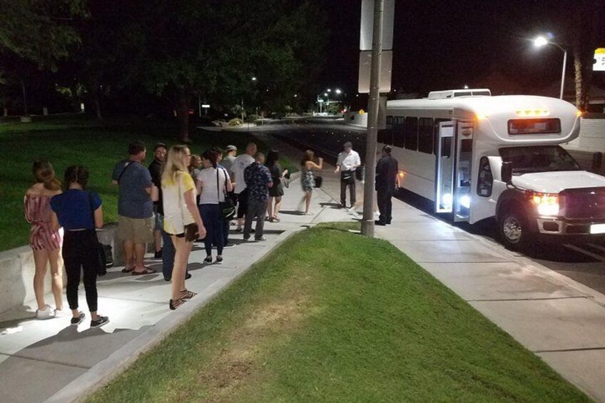 Un grupo de personas de pie en la acera junto a un autobús. 4