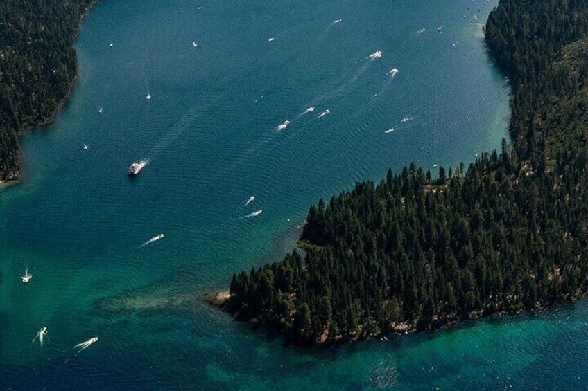 Una zona costera con una isla boscosa y varias embarcaciones en el agua. 3
