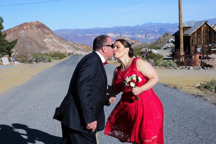 Una pareja besándose en una carretera con montañas al fondo. 5