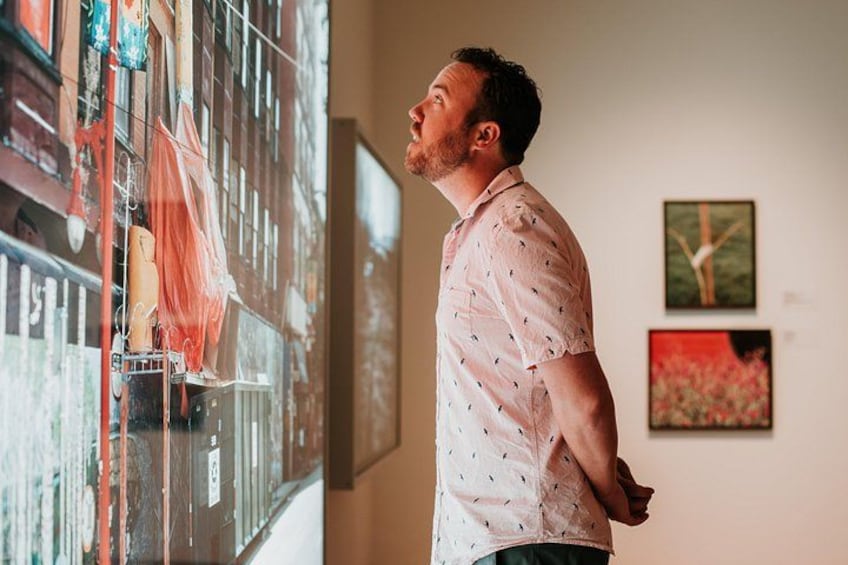 En person står indendørs og betragter en stor digital skærm med abstrakt kunst. 2