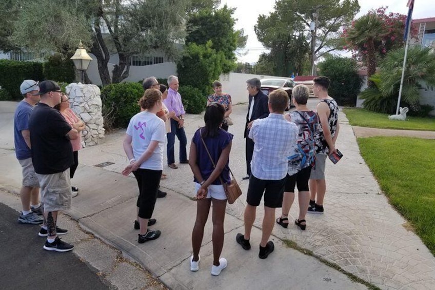 Un grupo de personas de pie en una acera en un barrio residencial. 1