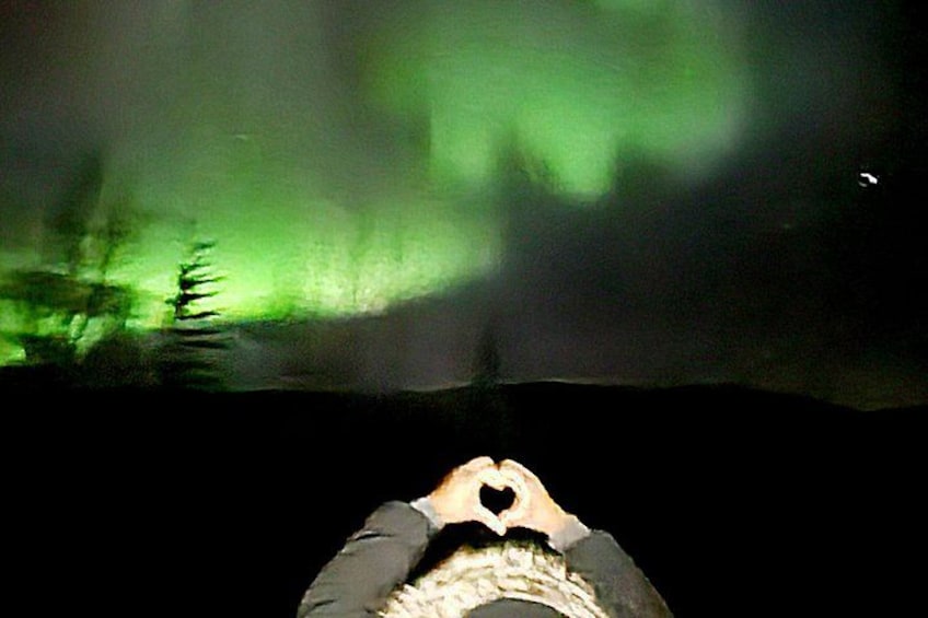 A person lying on a beach with a green aurora in the background. 4