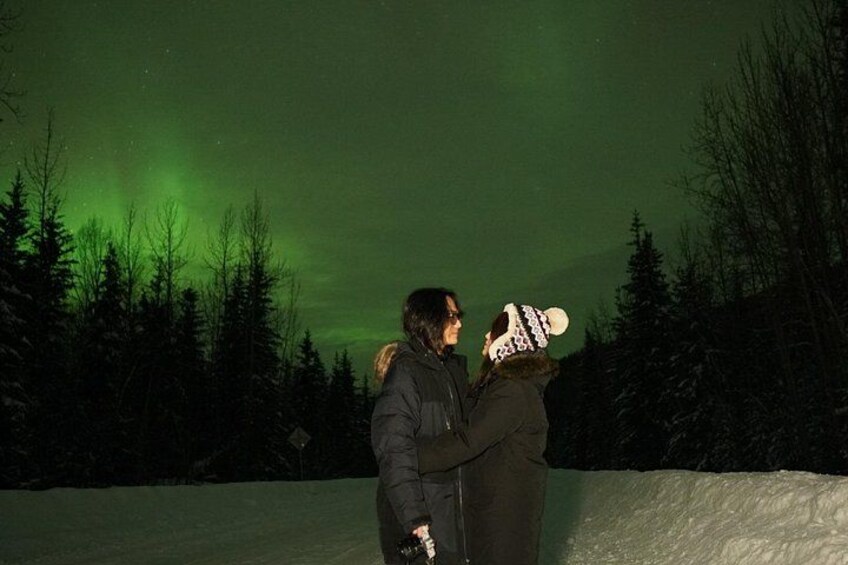 Two people standing in a snowy landscape under a green aurora. 3