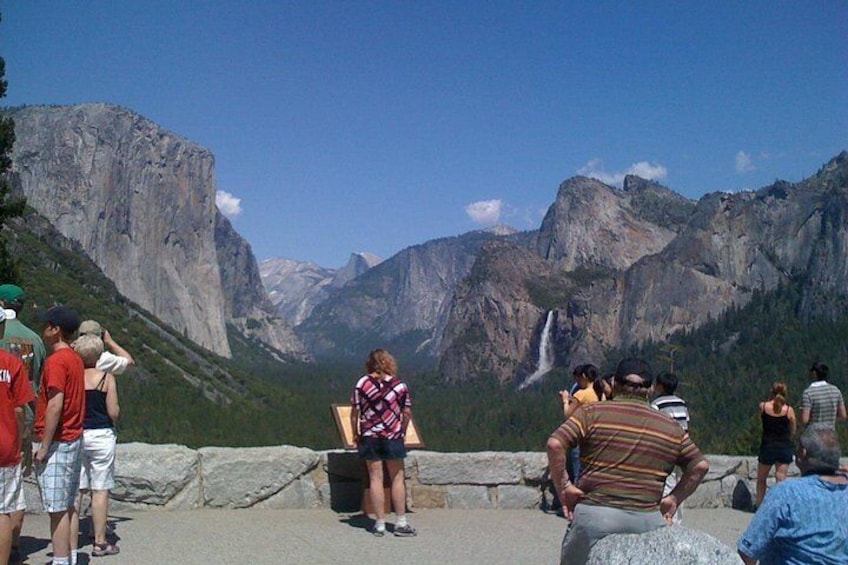 Un grupo de personas observando una cascada y una cordillera. 4