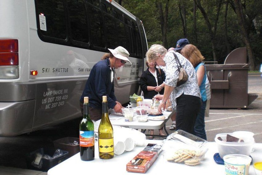 Un grupo de personas sirviendo comida en un evento al aire libre, con un autobús al fondo. 3