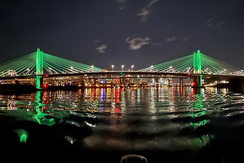 Un puente con iluminación verde que se refleja en el agua por la noche. 2