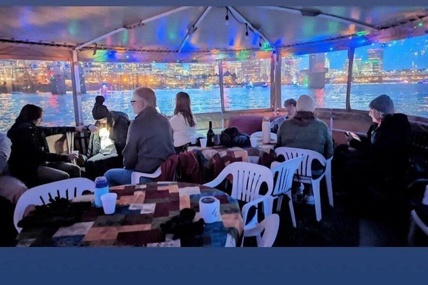 Un grupo de personas cenando en una mesa con vista a un horizonte urbano sobre el agua. 4