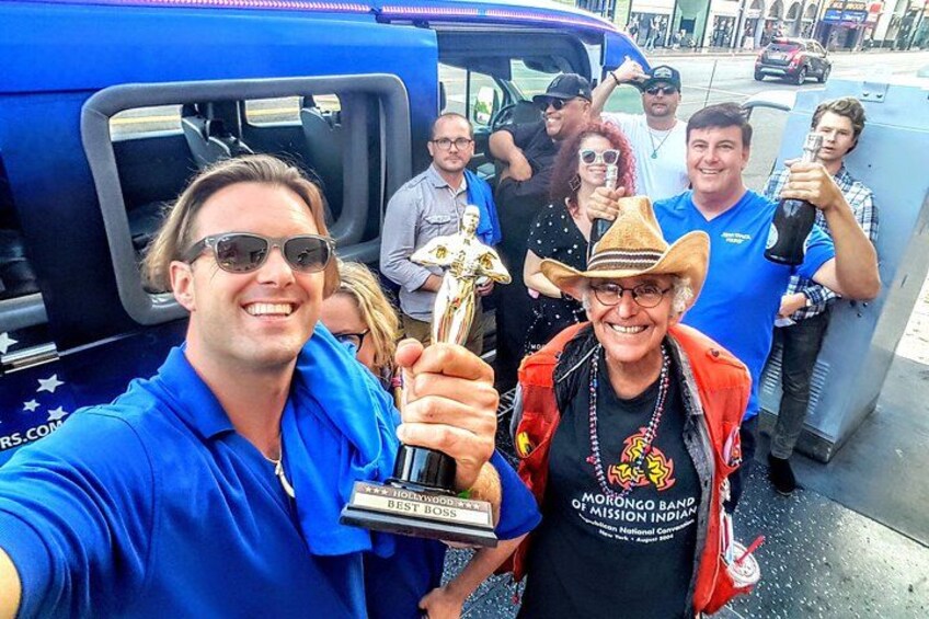 Un groupe de personnes tenant un trophée devant un véhicule bleu. 2