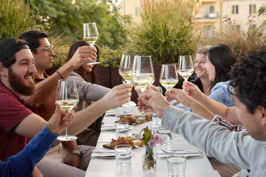 Un grupo de personas brindando con copas de vino en una mesa de comedor al aire libre. 1