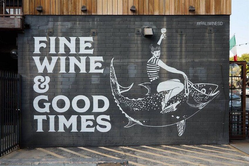 Un mural con el texto 'FINE WINE & GOOD TIMES' y una mujer en un bote. 5