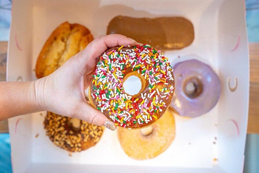 En hand som håller en chokladdonut med strössel. 3
