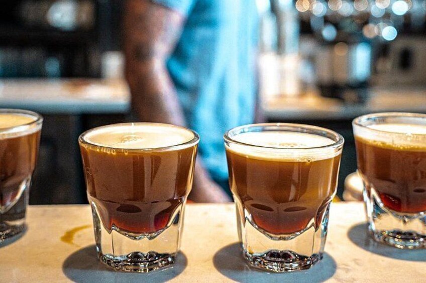 Tres vasos de una bebida oscura, posiblemente café, sobre una barra. 3