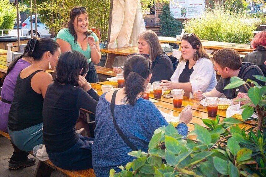A group of people sitting at an outdoor table, engaged in conversation. 5